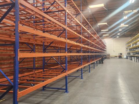 Rows of orange and blue pallet racking along a warehouse aisle