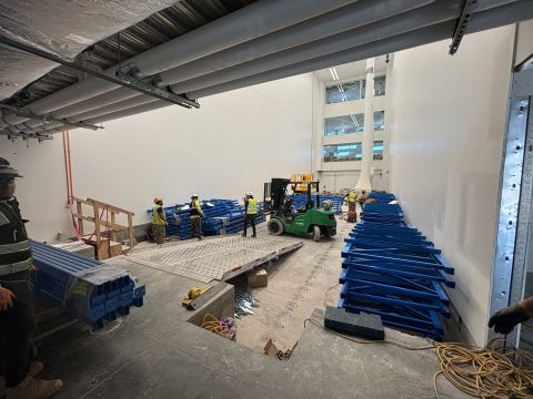Install crew unloading blue rack beams inside a warehouse