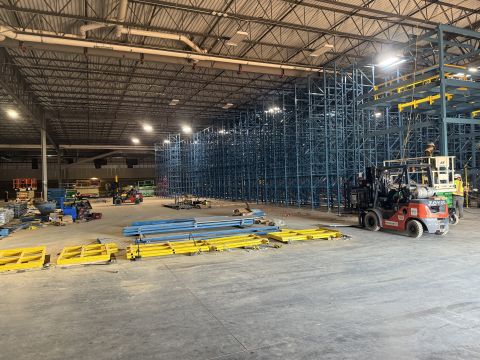 Pallet racking being installed in a large warehouse, with beams staged on the floor